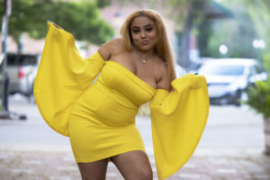 Senior girl in yellow dress with flowing arms in alley way. Outfit selection for senior portraits.