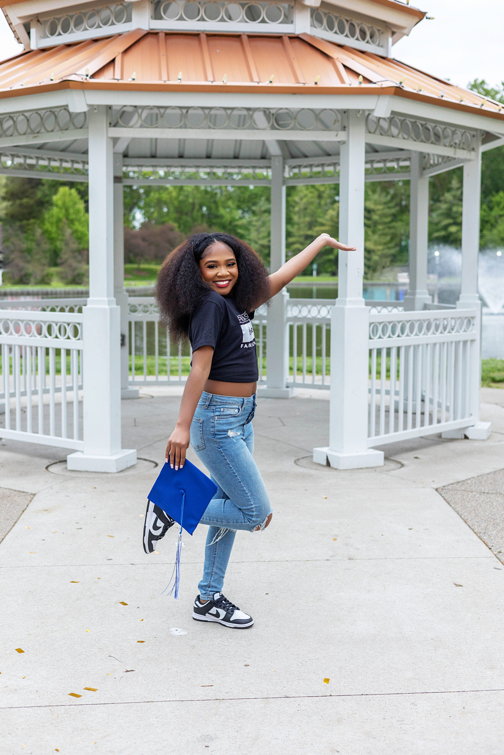 African American girl holding cap in front of a gazebo at Heritage Park in Taylor, Michigan posing for senior pictures.