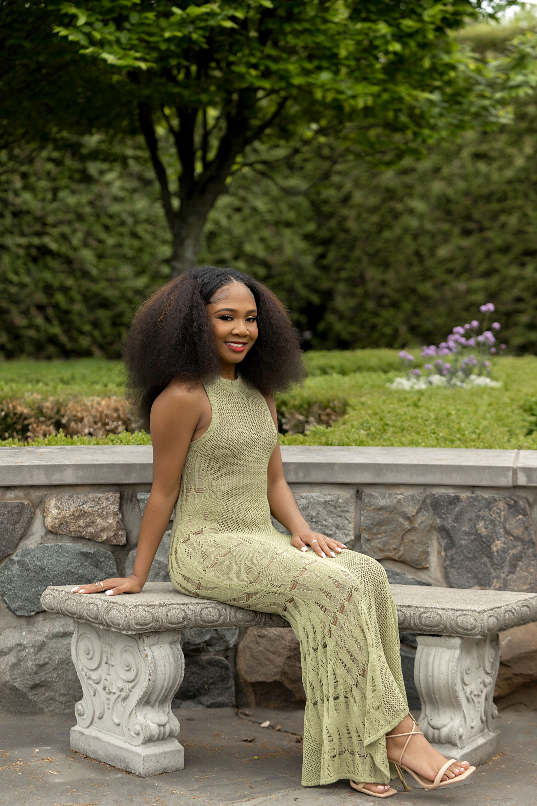 African American girl in green dress sitting on a bench at Taylor Botanical Gardens in Taylor, Michigan.